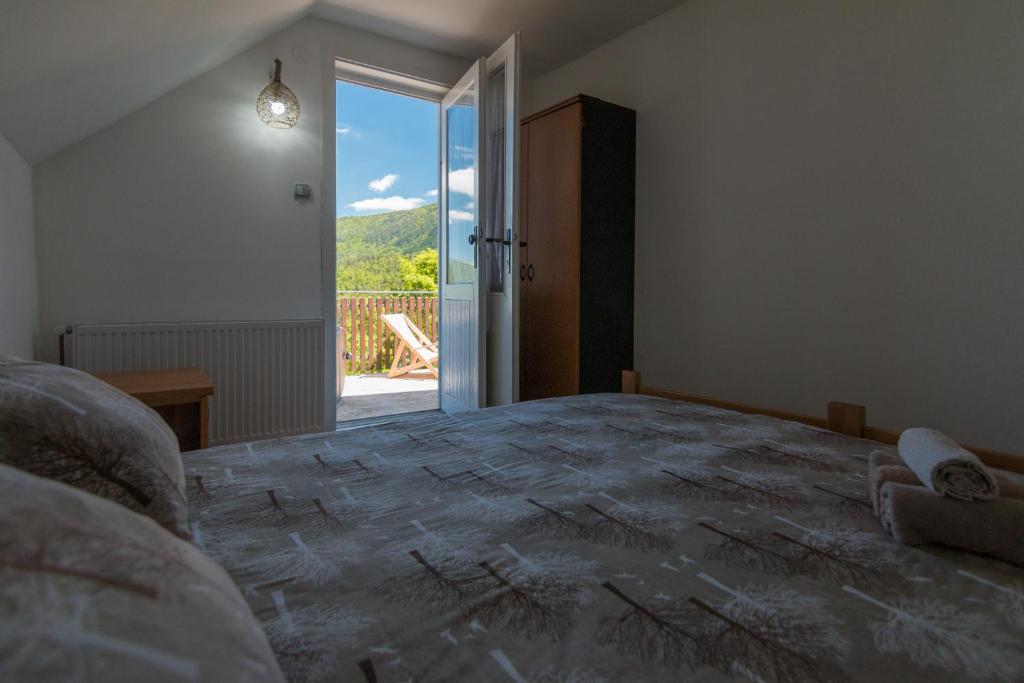 a bedroom with a large bed with an open door at Bogu iza nogu 2 in Bajina Bašta