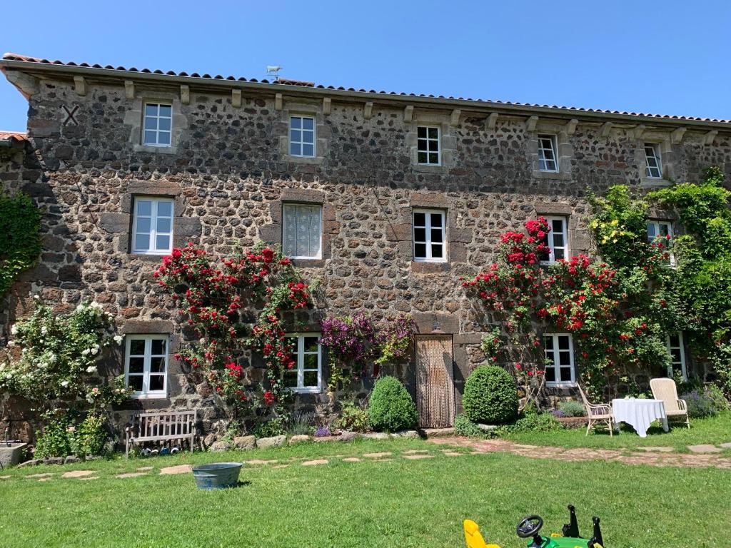 ein altes Steinhaus mit Blumen im Hof in der Unterkunft Le Potala in Le Bouchet-Saint-Nicolas