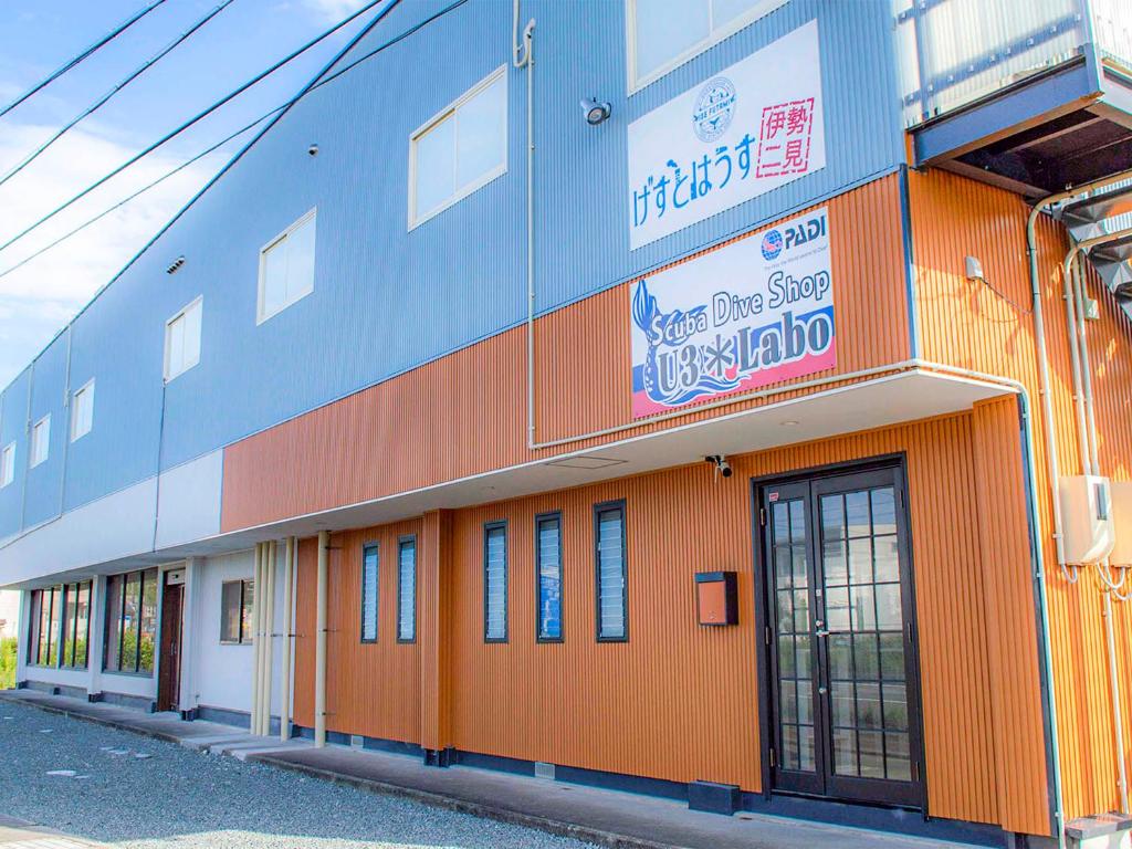 um edifício laranja e azul com um sinal nele em Guesthouse Ise Futami em Ise