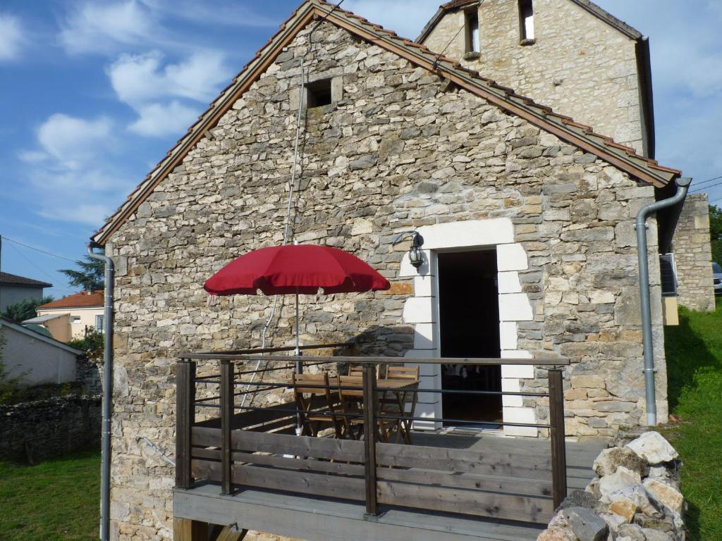 un pequeño edificio de piedra con una mesa y una sombrilla en Aux Pierres de Nozières, en Gramat