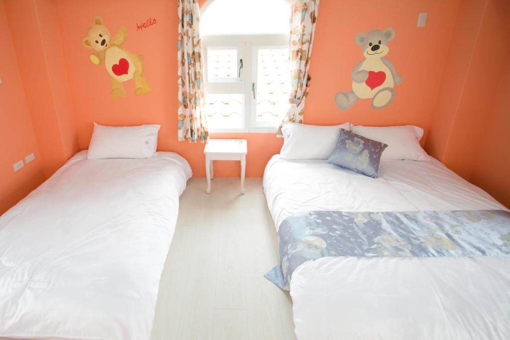 two twin beds in a room with orange walls at Decoupage Manor in Jiaoxi