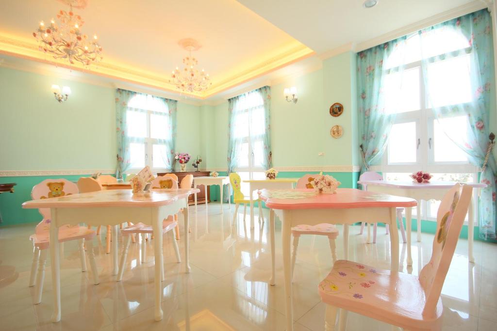 a dining room with tables and chairs and windows at Decoupage Manor in Jiaoxi