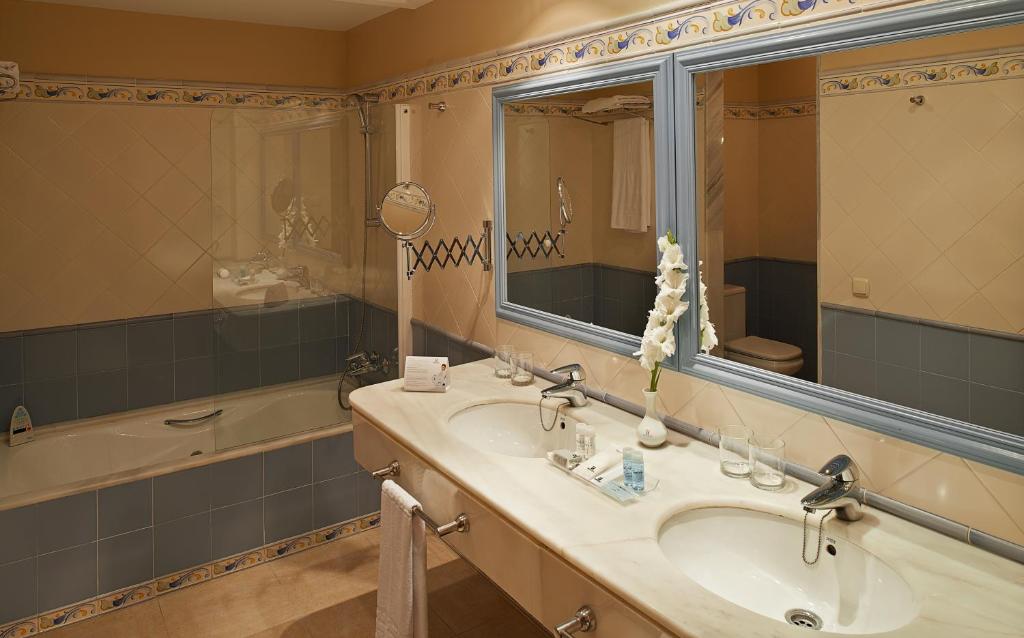 a bathroom with a sink and a mirror and a tub at Hipotels Barrosa Garden in Chiclana de la Frontera