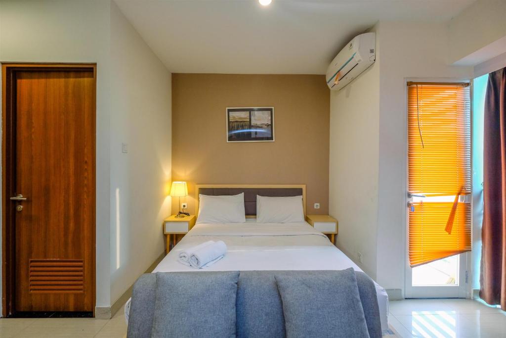 a bedroom with a large bed and a window at Modern and Spacious Studio with City View @ Grand Kamala Lagoon Apartment By Travelio in Pekayon Satu