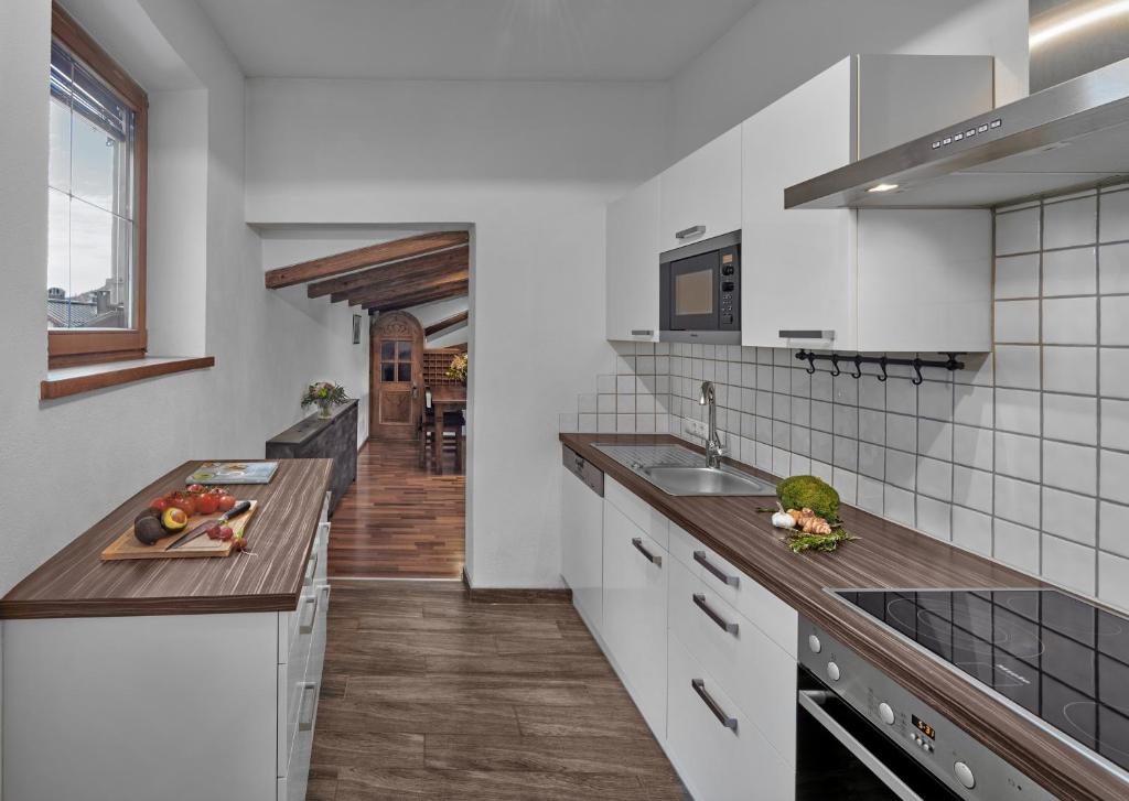 a kitchen with white cabinets and a wooden floor at Hotel Goldener Greif in Kitzbühel