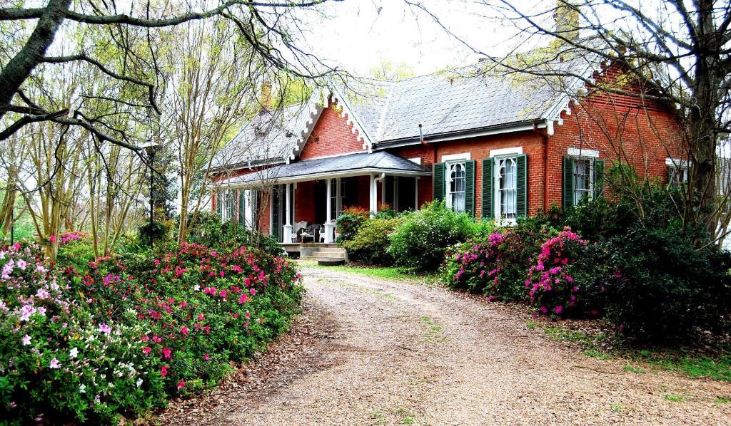 a red brick house with a dirt road in front at Glenfield Plantation Historic Antebellum Bed and Breakfast in Natchez