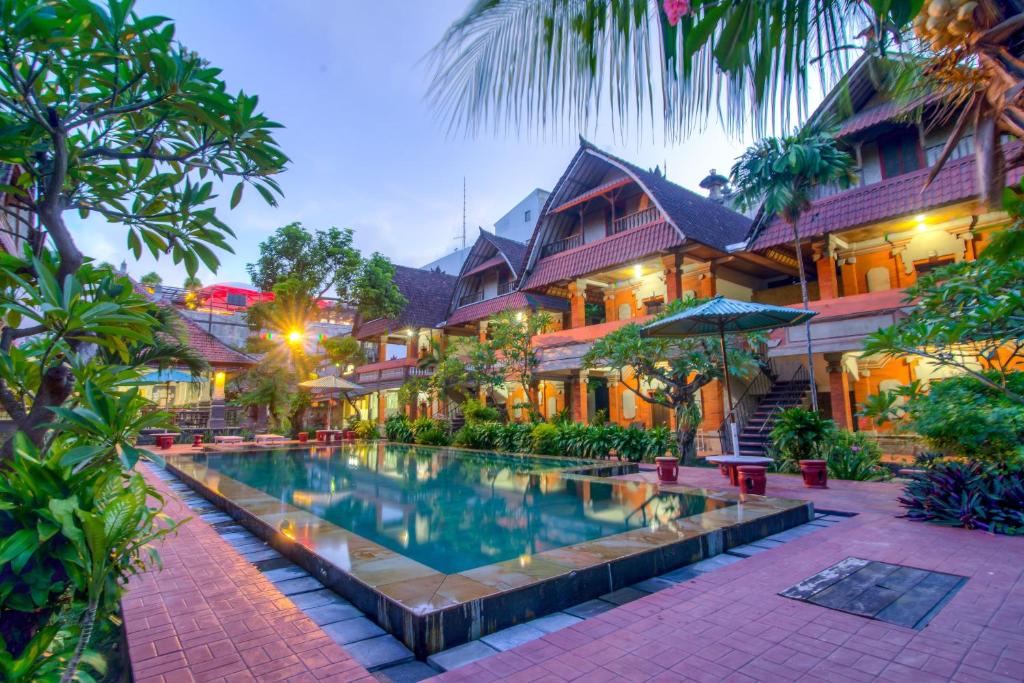 a resort with a swimming pool in front of a building at Troppo Zone Puri Rama Resort Kuta in Legian