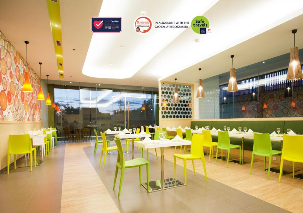 a dining room with tables and yellow chairs at Zest Jemursari by Swiss-Belhotel International in Surabaya