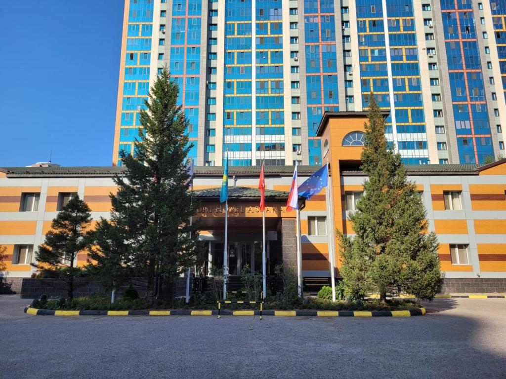 a large building with trees in front of it at Comfort Hotel Astana in Astana