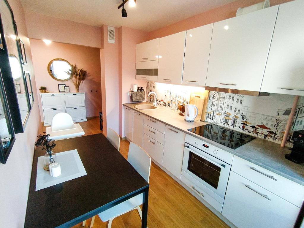 a kitchen with white cabinets and a black counter top at SUNSET Apartment Near Sea - family friendly space with bath and good coffee in Ventspils