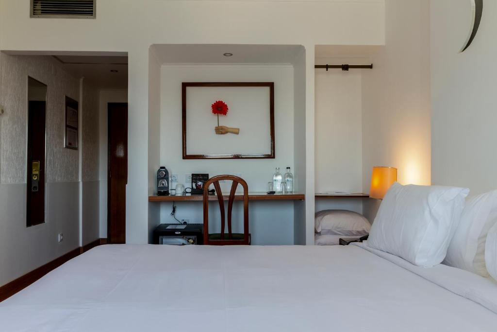 A bedroom view focused on the bed, compact desk and open shelving.