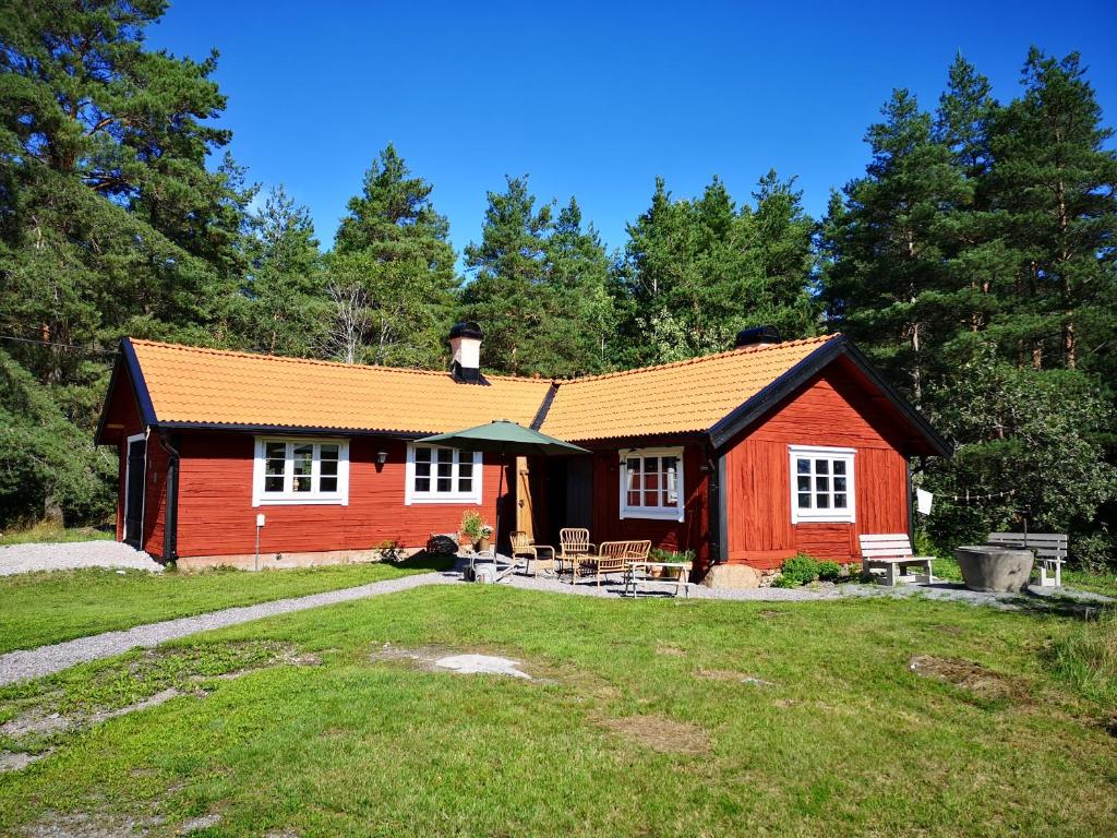 una pequeña casa roja con una mesa de picnic delante de ella en Smedjan cottage, en Enköping