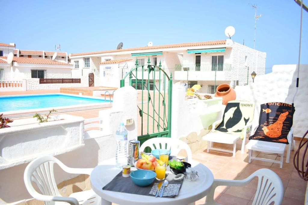 una mesa con comida en un balcón con piscina en Margherita's Apartment San Eugenio Costa Adeje, en Adeje