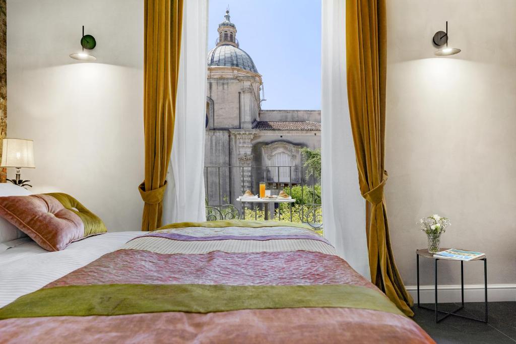 Schlafzimmer mit einem Bett und Blick auf ein Gebäude in der Unterkunft Relais Antica Badia - San Maurizio 1619 in Ragusa