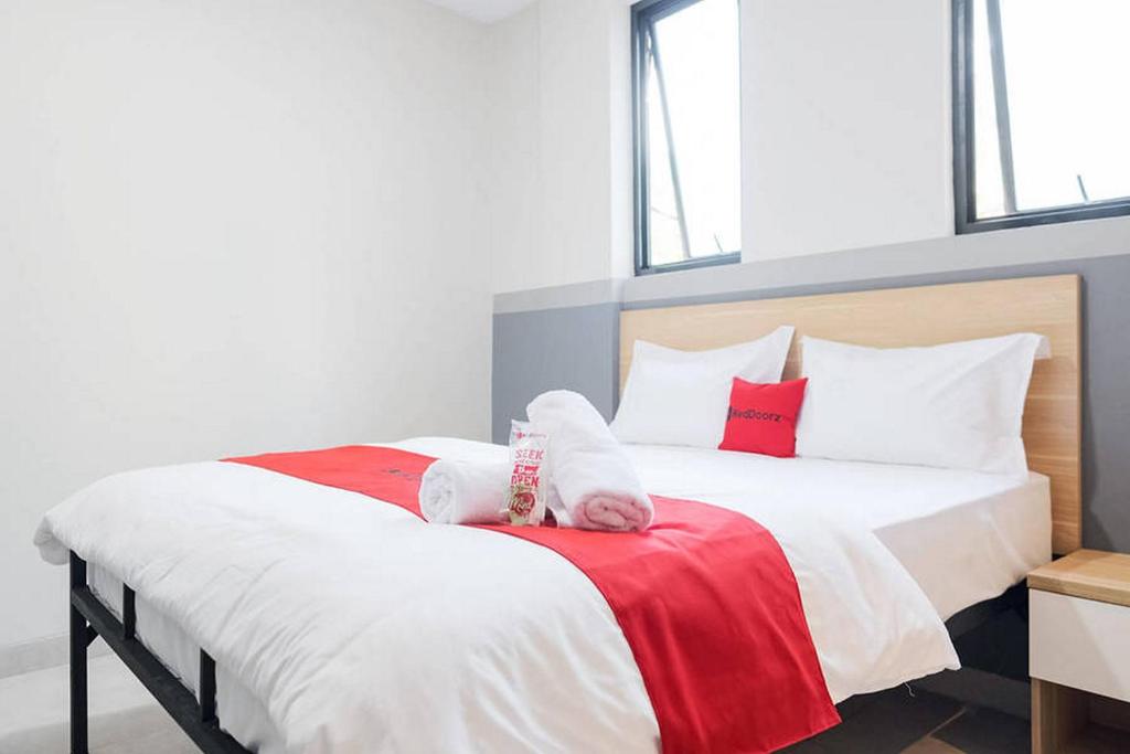 a bedroom with a large bed with red and white sheets at RedDoorz Plus near Taman Anggrek Mall in Jakarta