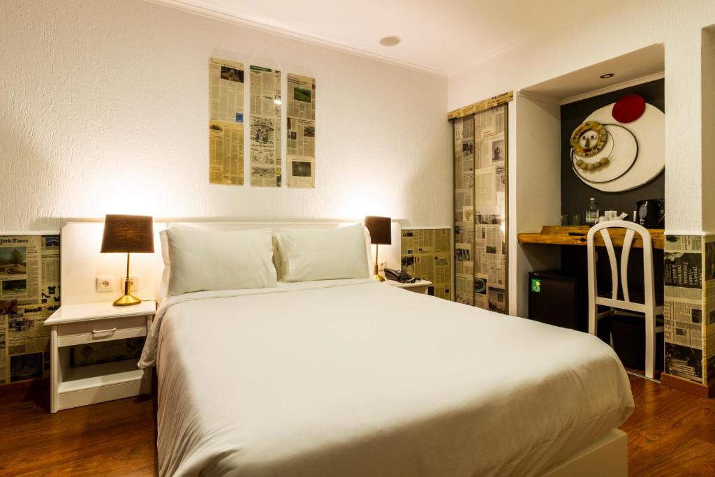 A themed double room with newspaper-print décor, a white bed and a compact desk.