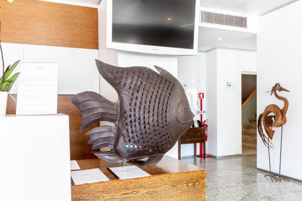 A fish sculpture displayed on a wooden reception or lobby table beneath a television.
