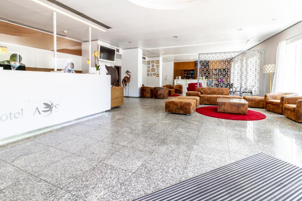 A spacious, modern lobby offers leather seating around a red circular rug.