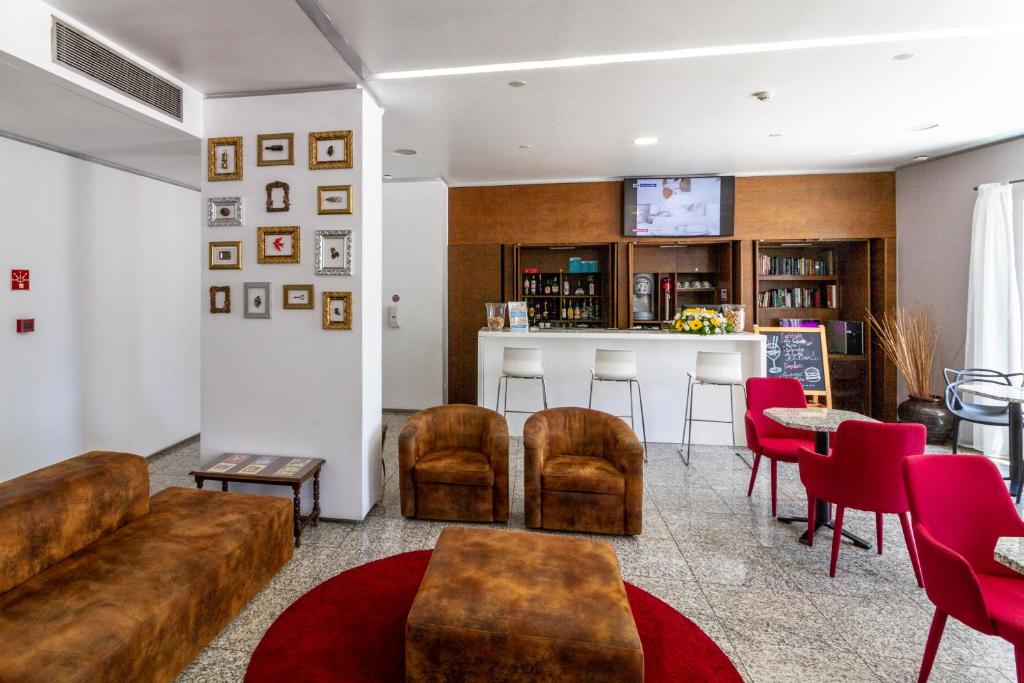 A hotel lounge and bar with leather seating, red chairs, bookshelves, and a television.