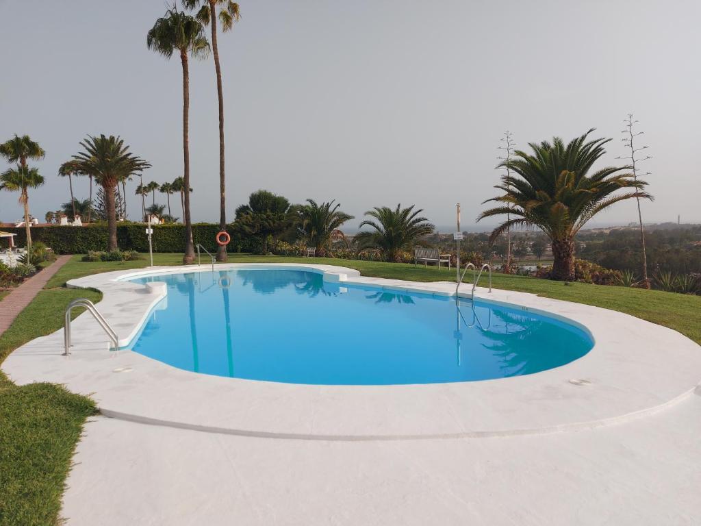 a swimming pool in a resort with palm trees at Villa in Duna Golf in Playa del Ingles