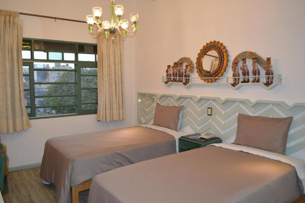 two beds in a room with a window and a chandelier at Collacocha B&B in Lima