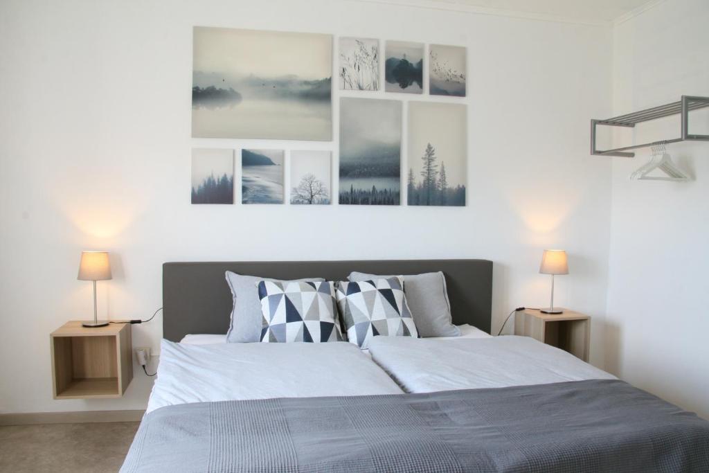 a bedroom with a large bed with three pictures on the wall at Haus Luna in Butgenbach