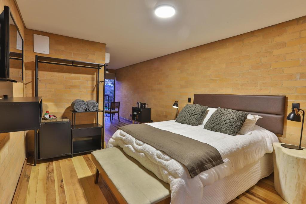 a bedroom with a large bed and a brick wall at DOM Hotel in Campos do Jordão
