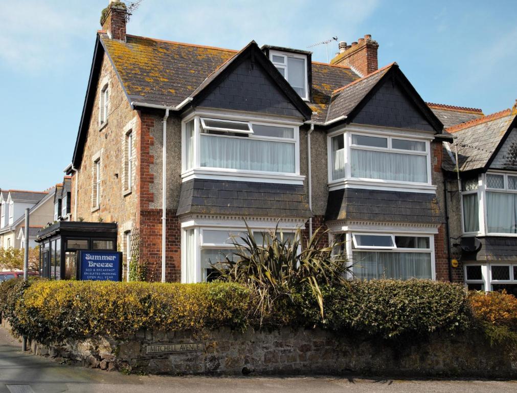 a brick house with white windows on a street at Summer Breeze in Newquay