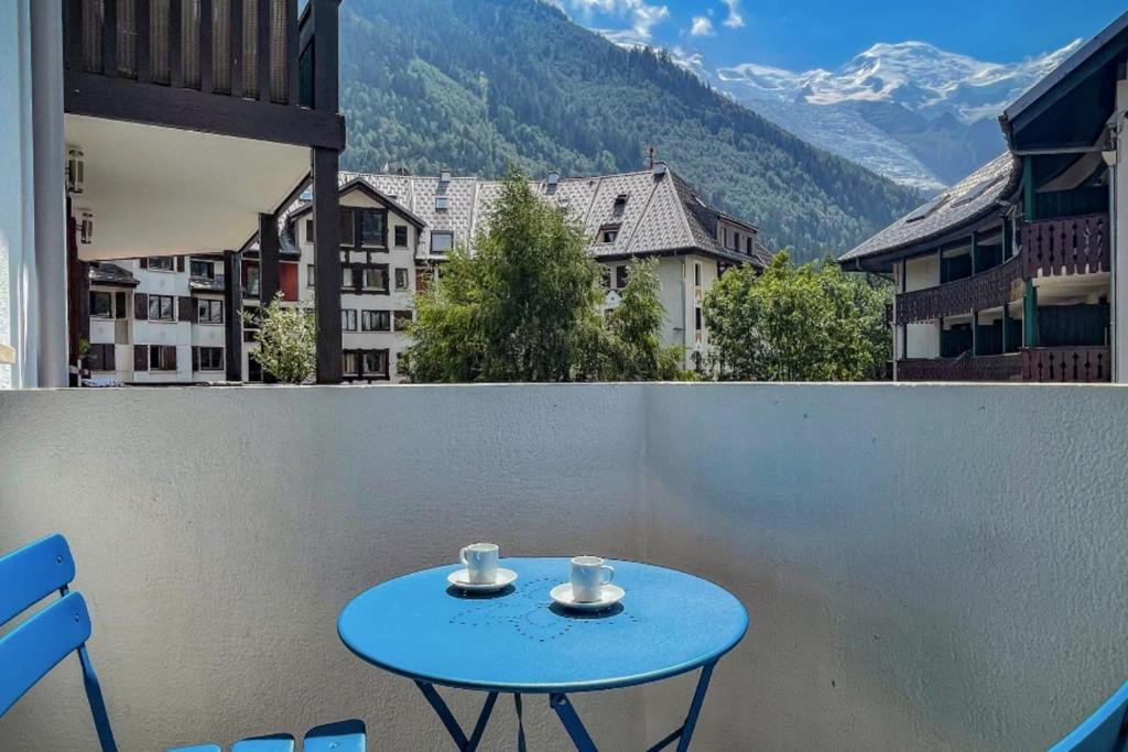 a blue table on a balcony with a view of mountains at Nice Apt With Mountain View At The Foot Of Slopes in Chamonix-Mont-Blanc
