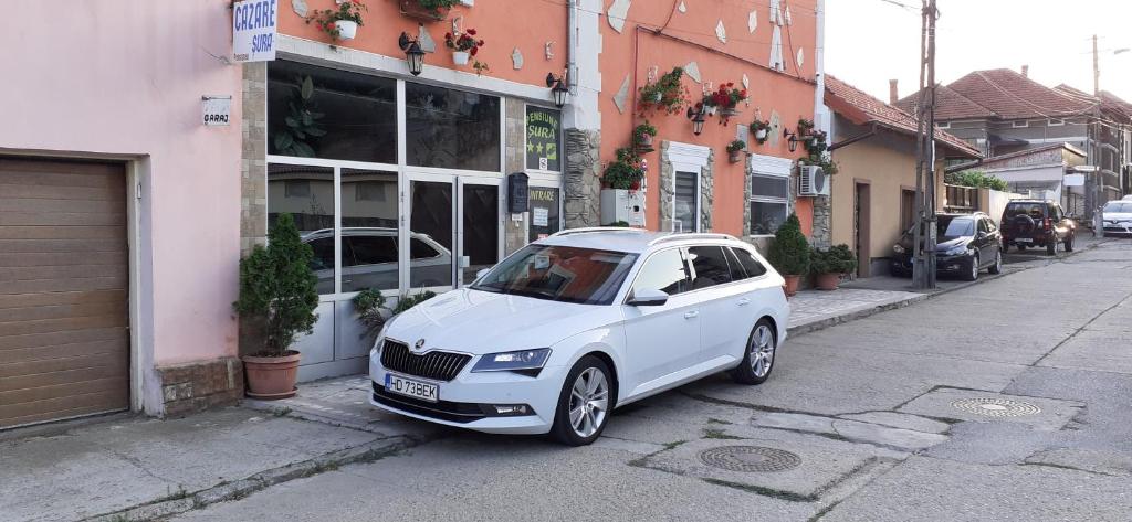 a white car parked in front of a building at Pensiunea Sura in Orăştie