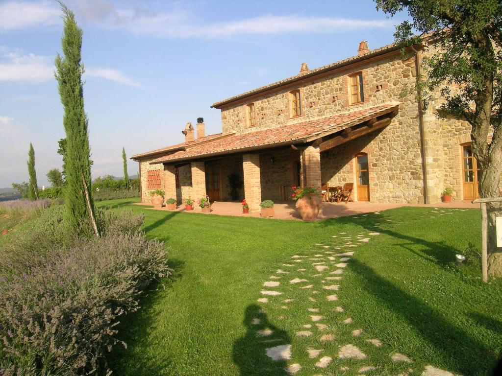 a large stone house with a grass yard at Villa Le Ginestre in Parrano