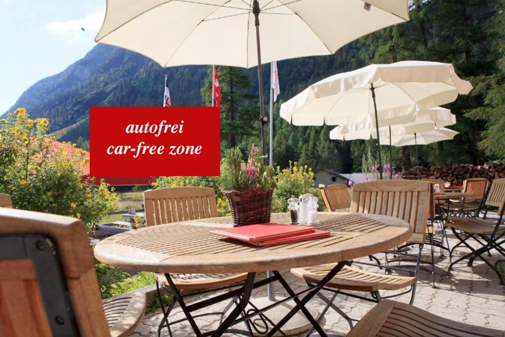 einen Tisch und Stühle mit Sonnenschirmen und ein Schild, das autorisierte Autobrände liest in der Unterkunft Gasthaus Spinas in Bever