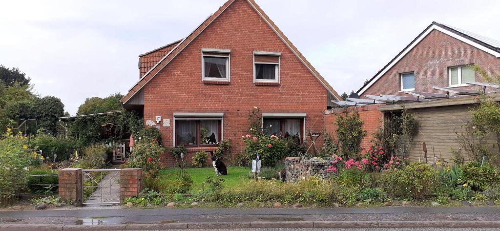 a brick house with a cat sitting in the yard at Ferienwohnung-Wildblume in Petersdorf auf Fehmarn