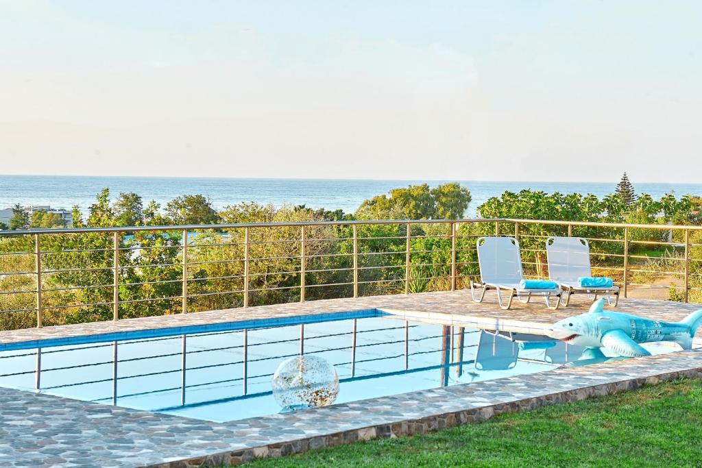 uma piscina com duas cadeiras e uma mesa e uma piscina em Villa Rose em Georgioupolis