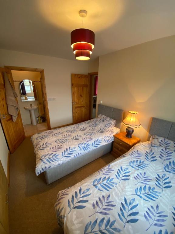 a bedroom with two beds and a lamp in it at Castlebaldwin Country Residence in Sligo