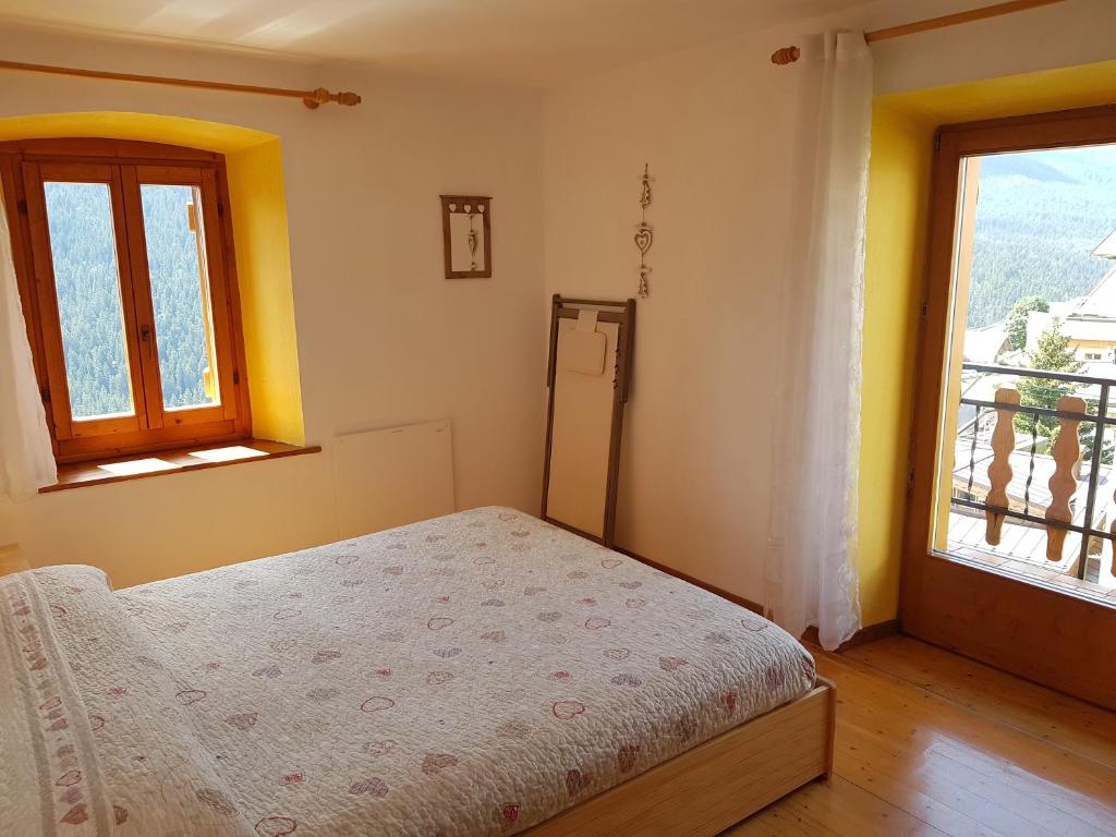 een slaapkamer met een bed en twee ramen bij Appartamento Comelico Dolomiti in Candide