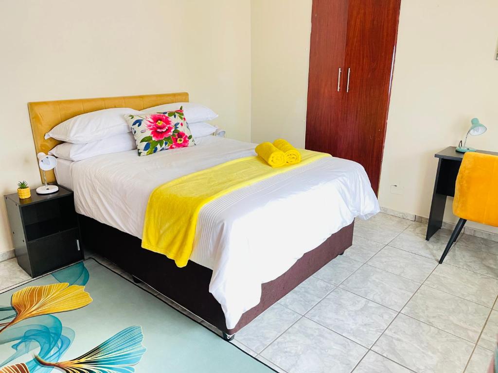 a bedroom with a bed with a yellow blanket on it at The Home in Richards Bay
