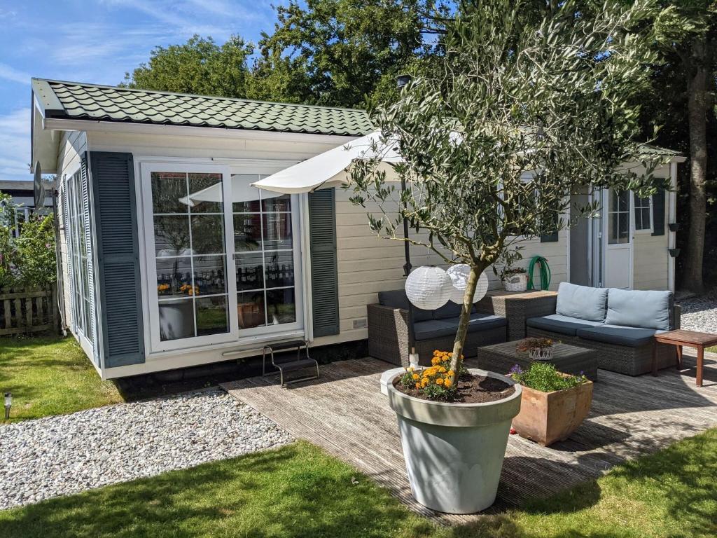 a small shed with a tree in a yard at Charming Chalet in Goedereede with Open Area in Goedereede