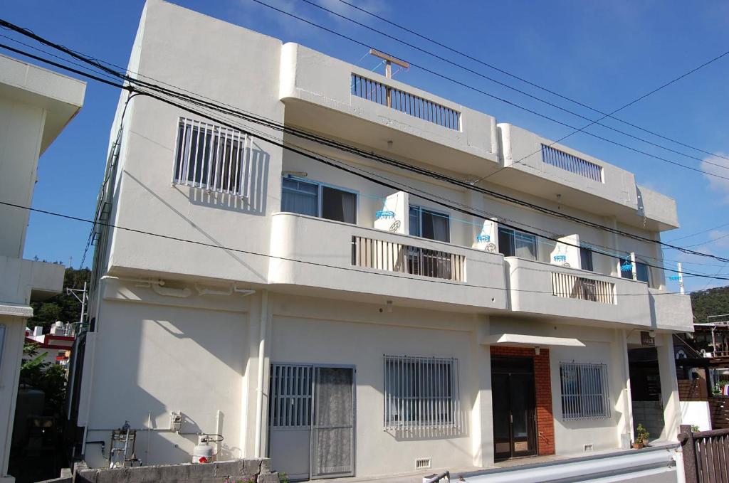 a white building with balconies on a street at Guesthouse Iyonchi in Zamami
