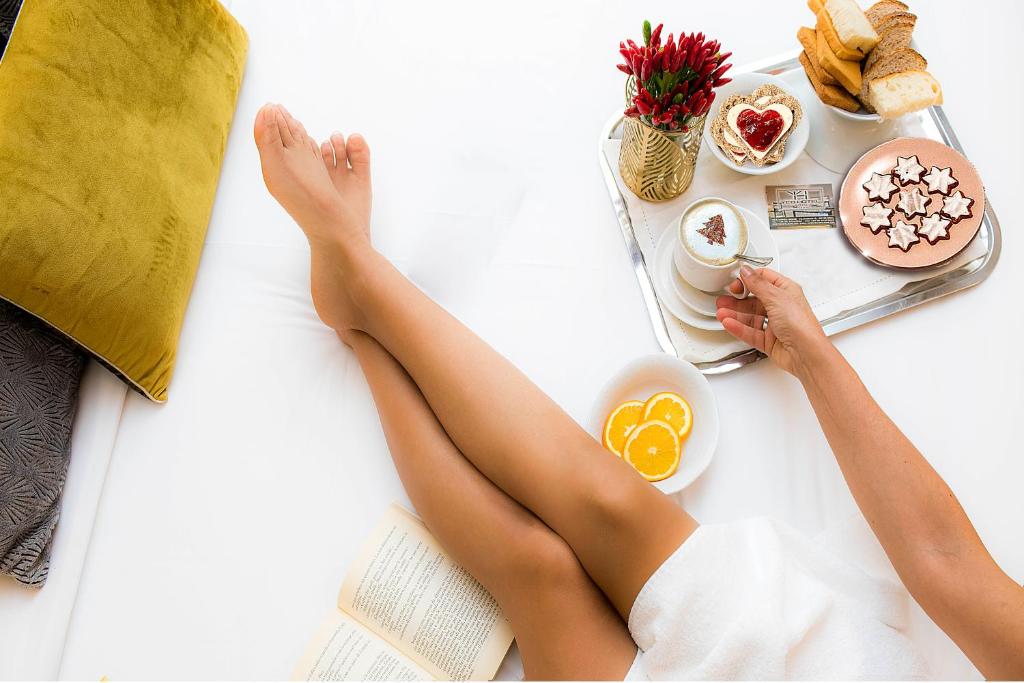 una mujer acostada en una cama con sus piernas en una bandeja de comida en Yes Hotel Boutique Rome, en Roma