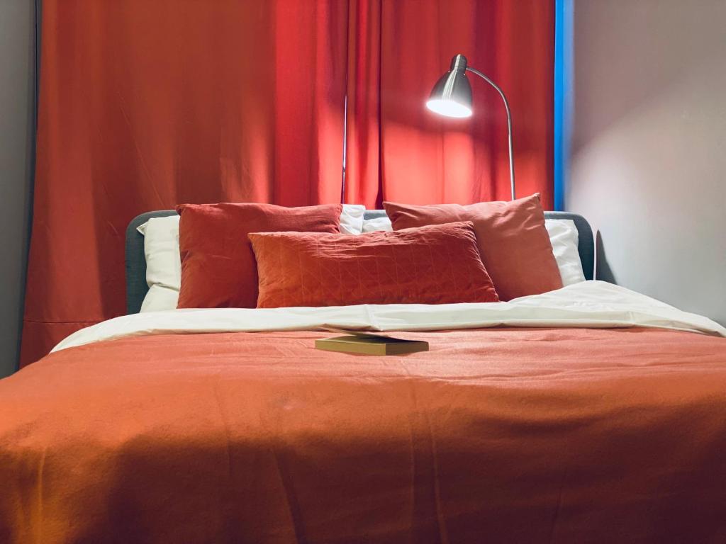1 dormitorio con 1 cama con cortinas rojas y lámpara en Flamingo apartment (FA), en Riga