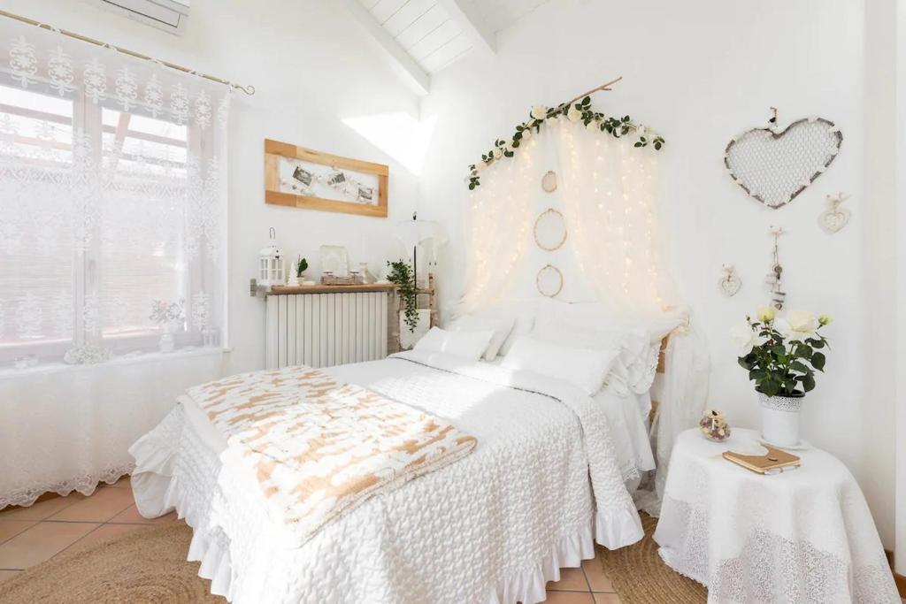 Dormitorio blanco con cama y pared de corazón en Il Gelsomino di Ossuccio, en Ossuccio