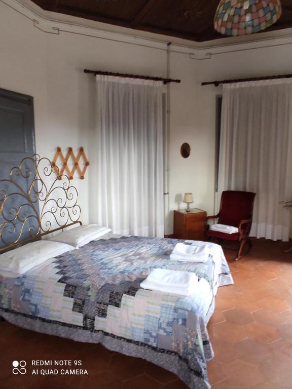 1 dormitorio con 1 cama y 1 silla en Agriturismo Villa Brugolta, en Lavena Ponte Tresa