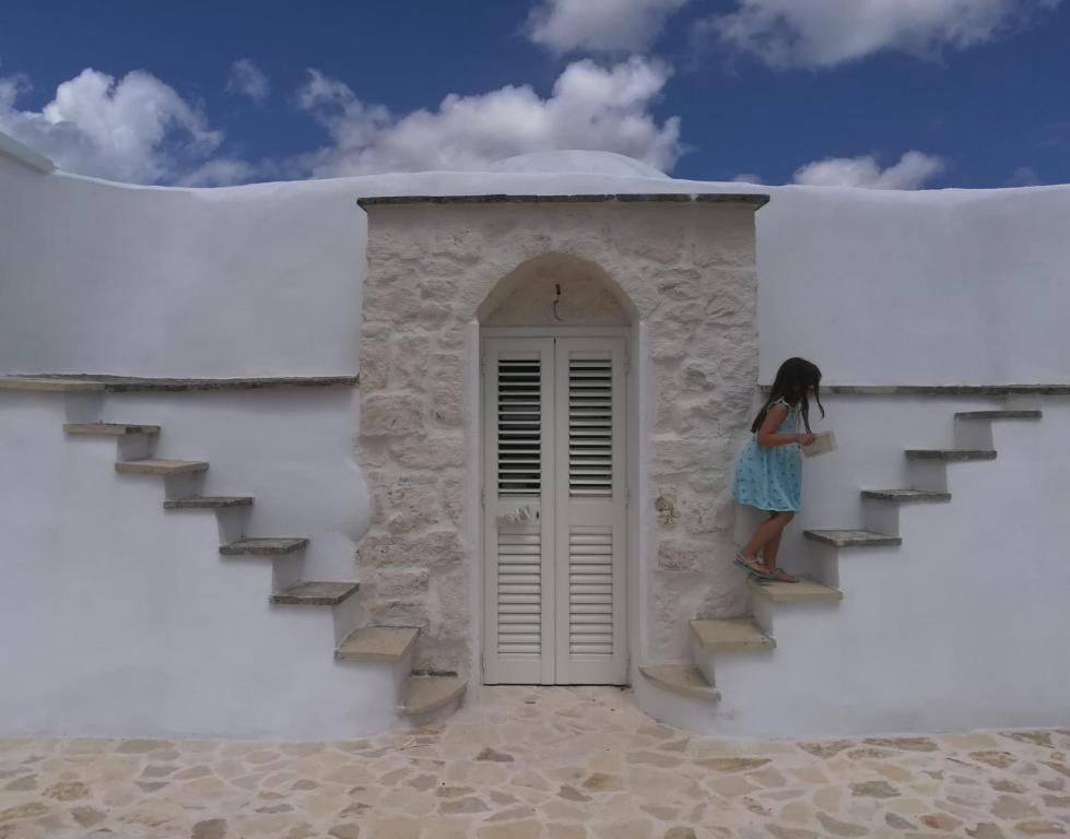 a girl standing on the stairs of a white building at Fiore di Cappero in Ostuni