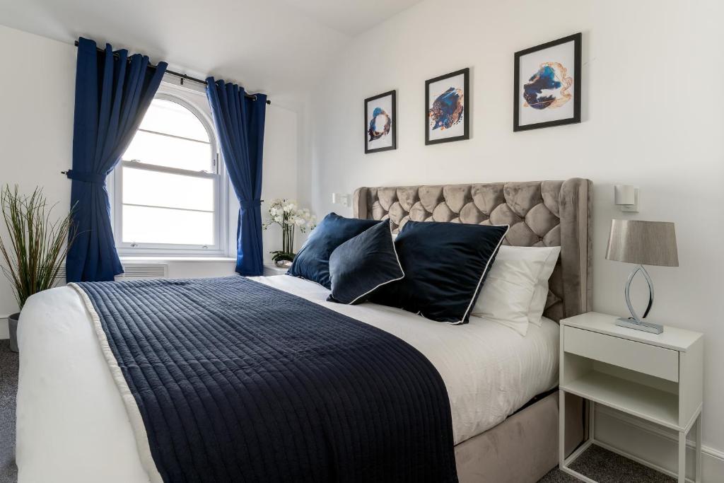 a bedroom with a bed with blue curtains and a window at Torquay Heights Modern Apartments in Torquay