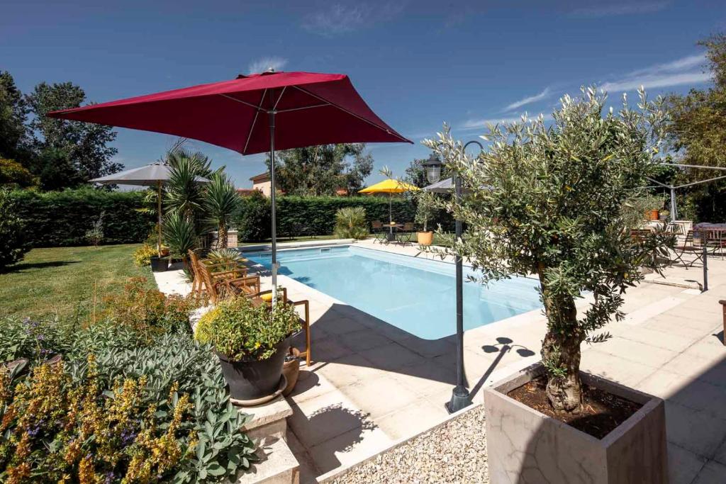 a swimming pool with a red umbrella next to it at Merveilleuses chambres d'hôtes à Panazol in Panazol