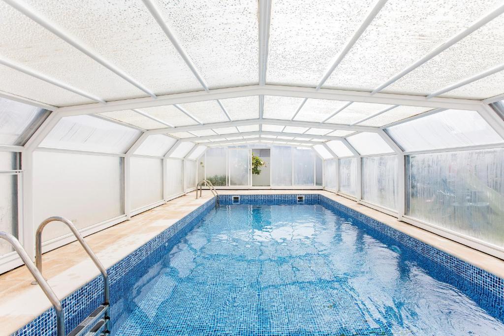 an indoor swimming pool with a glass ceiling at Mindelo 3BDR Duplex House W/Pool in Mindelo