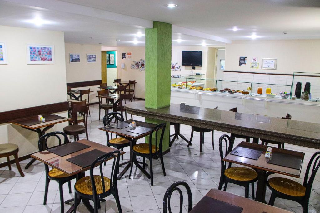 un restaurante con mesas, sillas y una barra en Hotel Acalanto en Feira de Santana