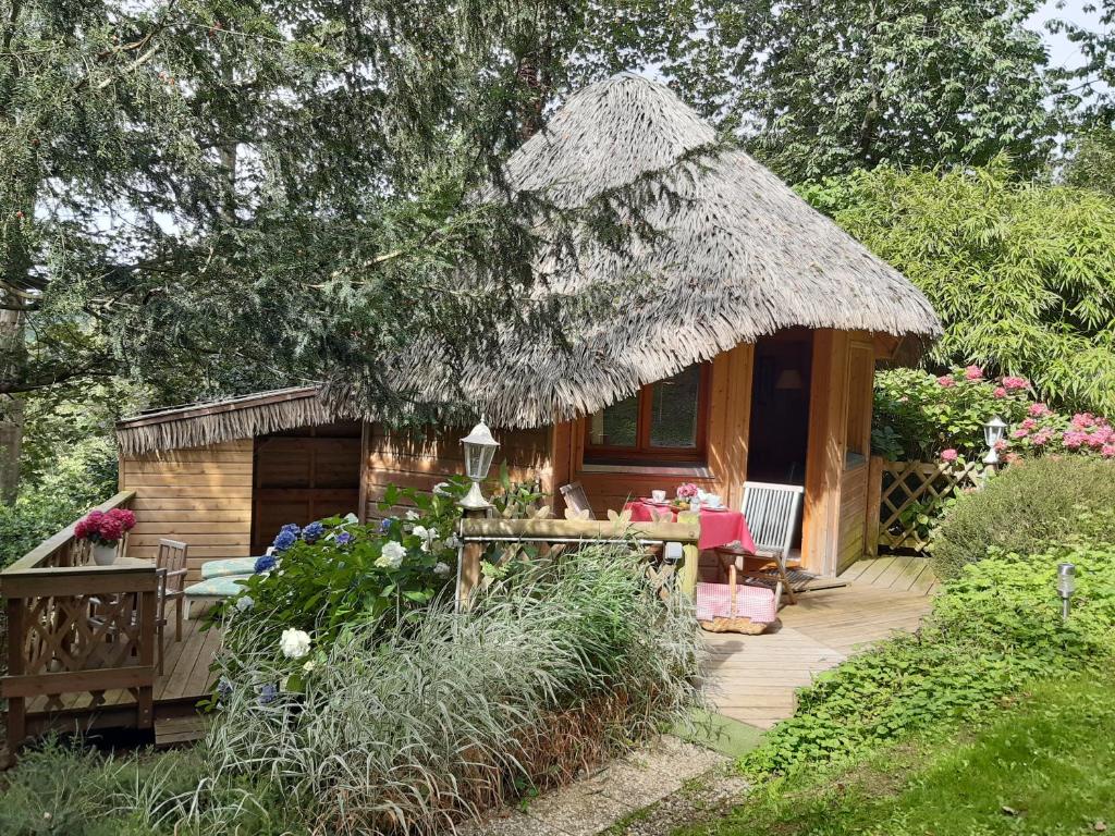 a small wooden cabin with a thatch roof at La Cabane de Cécile-la Hutte in Étretat