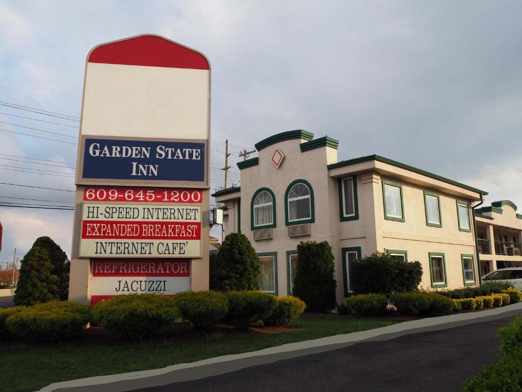 una señal para una posada en el estado del jardín frente a un edificio en Garden State Inn en Absecon